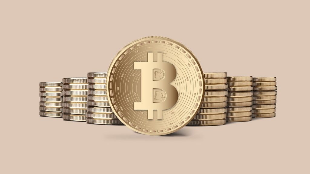 Stack of golden coins with a large central coin displaying the Bitcoin symbol, set against a plain beige background.