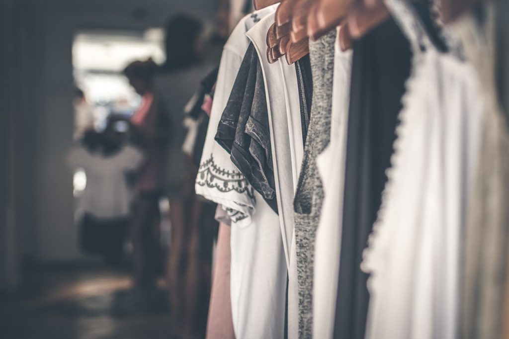 Several garments, likely shirts or kurtas, are hanging on a rack, showcasing intricate designs and patterns.