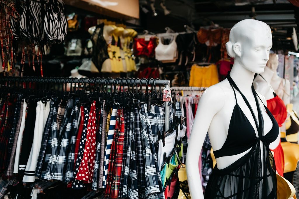 A mannequin wearing a black dress with white accents stands in a clothing store.
