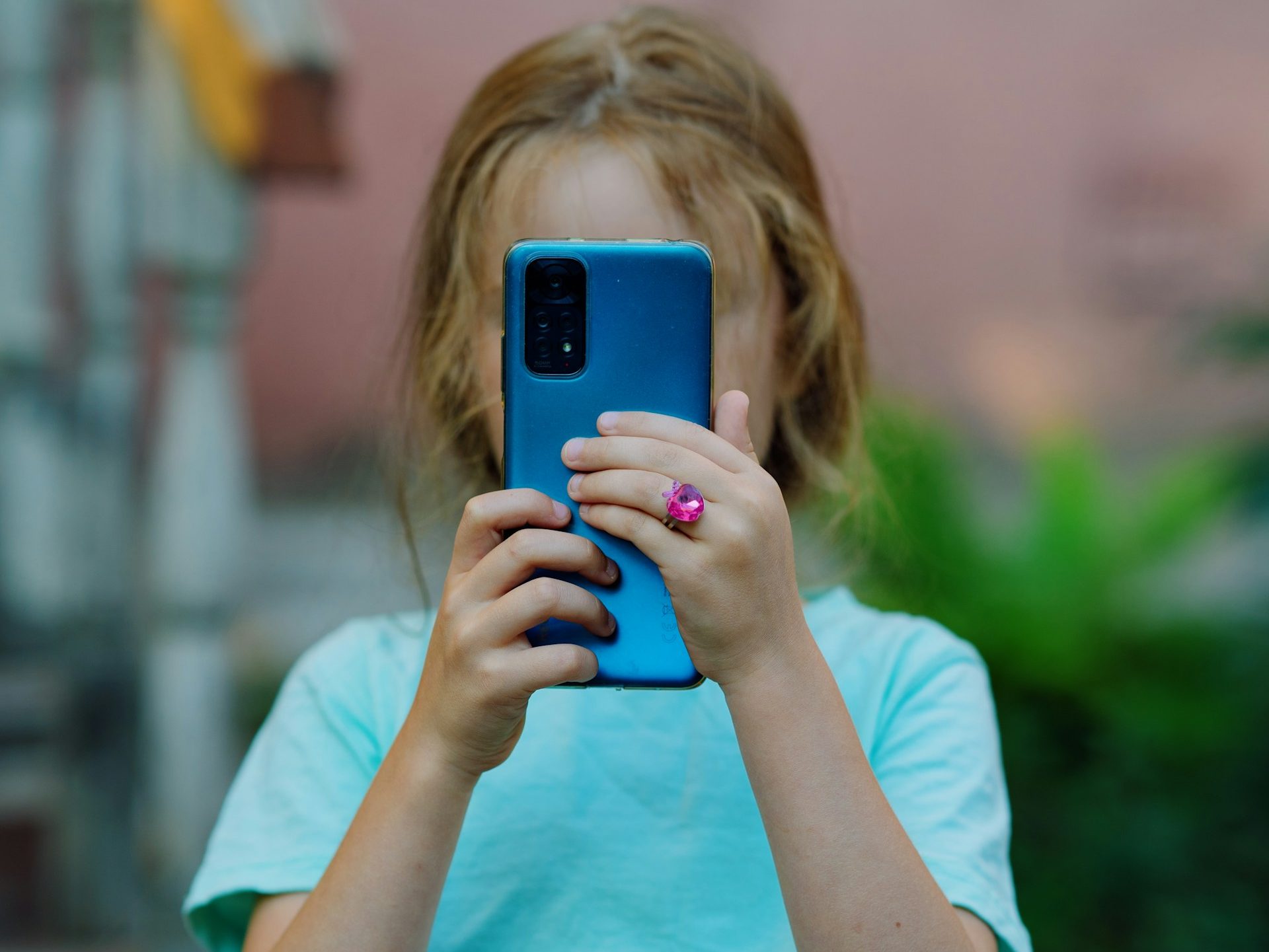 A small girl holding a blue mobile phone.