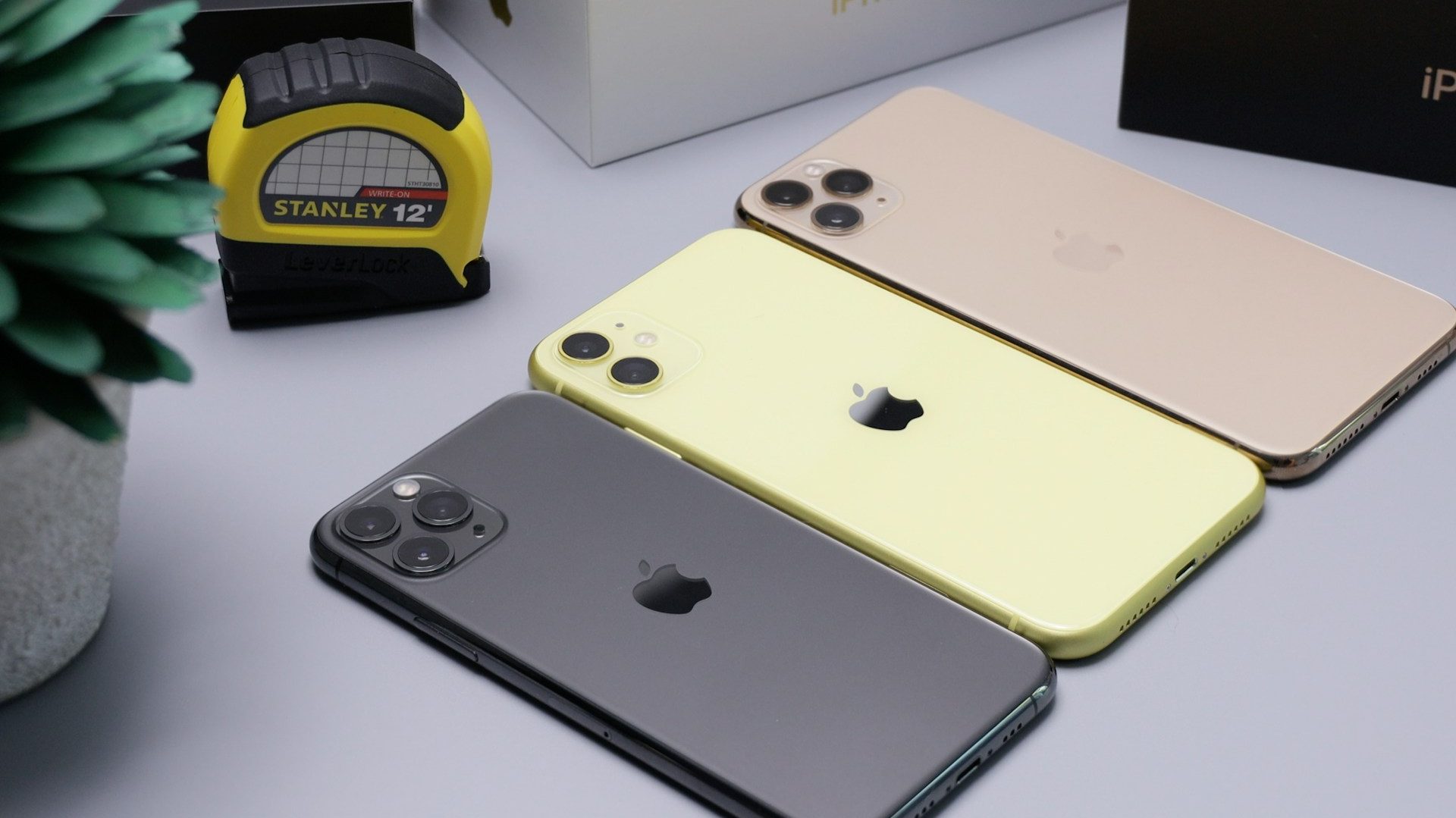 Three imported iPhones in different colours displayed on a table, representing Pakistan’s $1.36B mobile phone imports during FY25.