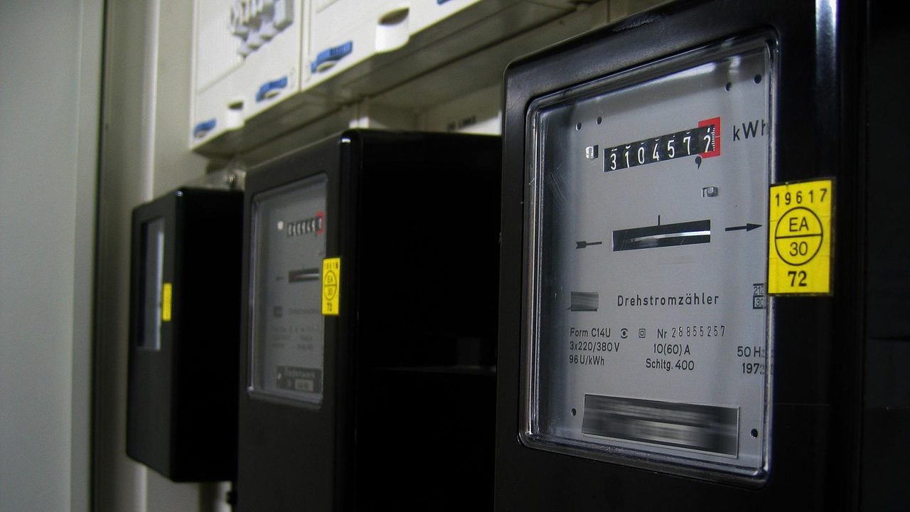 Close-up of traditional electricity meters mounted on a panel, highlighting energy consumption monitoring amidst rising energy costs and new clean energy taxes.