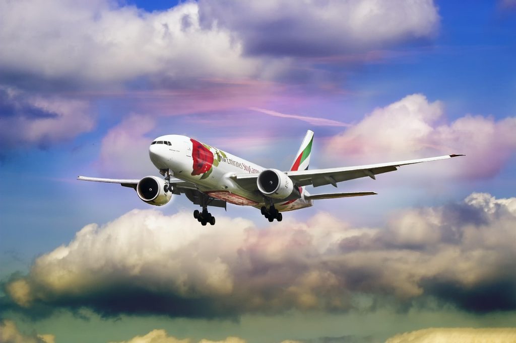 An Emirates aircraft in mid-air against a vibrant, cloudy sky, symbolizing the smooth resumption of the airline’s regular flight operations.