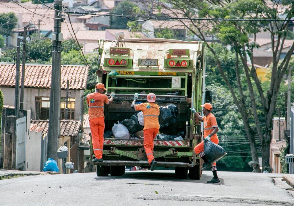 Sanitation workers collecting garbage from residential streets using a garbage truck, representing the beginning of garbage tax collection efforts in Punjab.