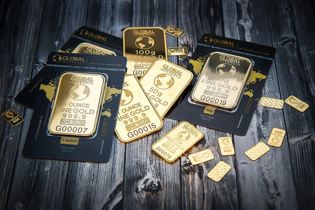 Gold bars and smaller gold pieces on a blue surface.
