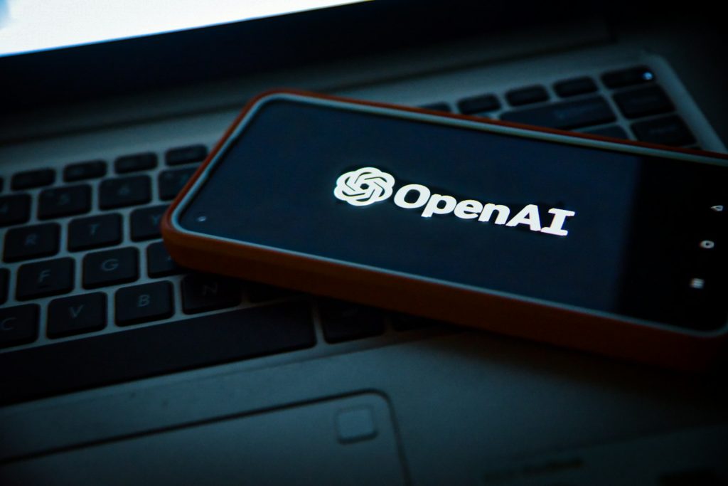 Smartphone displaying the OpenAI logo placed on a laptop keyboard, symbolizing OpenAI's technological collaboration and advancement—relevant to OpenAI winning a $200M contract with the US military.