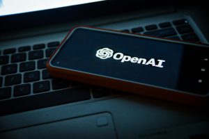 Smartphone displaying the OpenAI logo placed on a laptop keyboard, symbolizing OpenAI's technological collaboration and advancement—relevant to OpenAI winning a $200M contract with the US military.