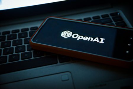 Smartphone displaying the OpenAI logo placed on a laptop keyboard, symbolizing OpenAI's technological collaboration and advancement—relevant to OpenAI winning a $200M contract with the US military.