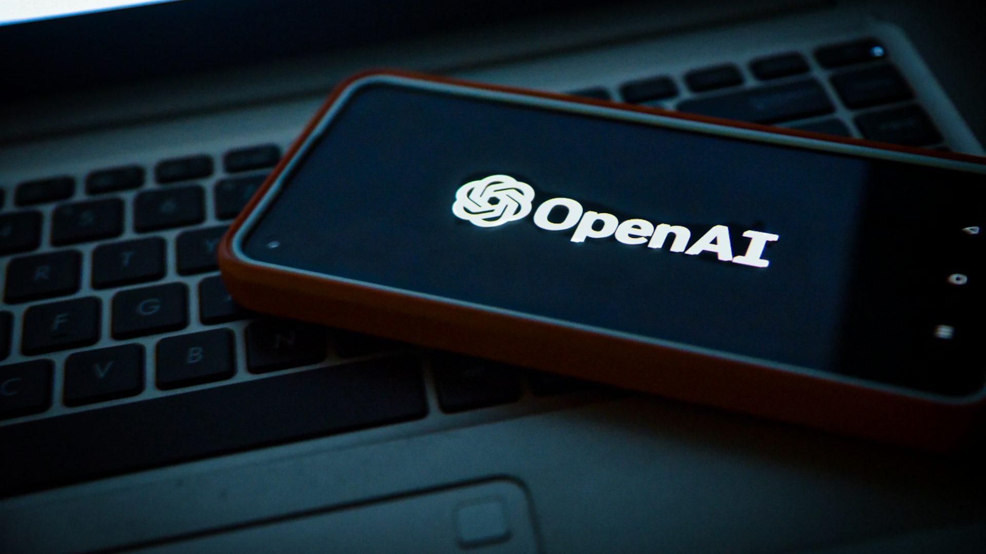 Smartphone displaying the OpenAI logo placed on a laptop keyboard, symbolizing OpenAI's technological collaboration and advancement—relevant to Youth Turn to AI Chatbots for News.