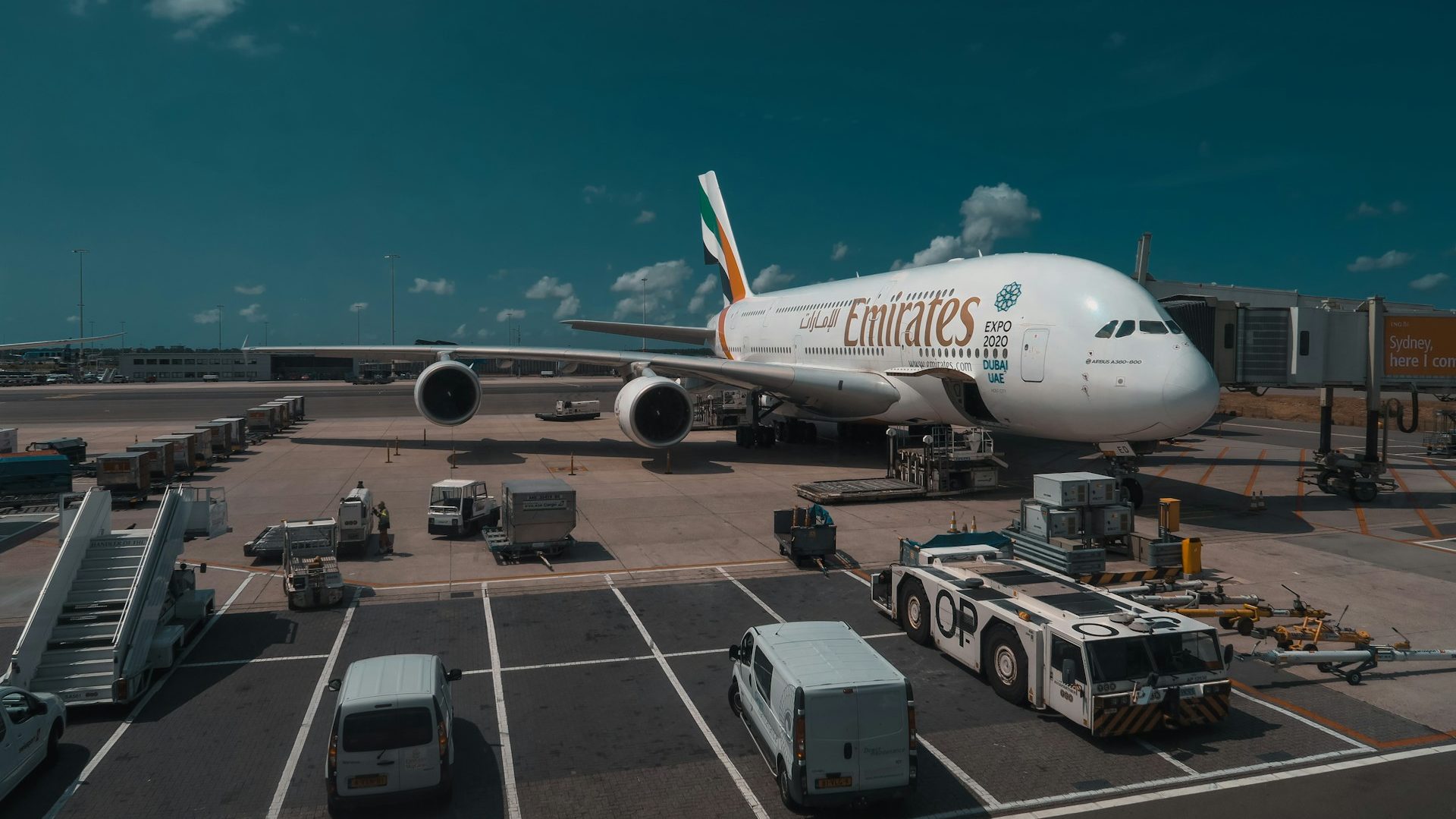 Emirates Airbus A380 parked at an airport gate with ground support vehicles surrounding it, highlighting the smooth return of scheduled flight operations.