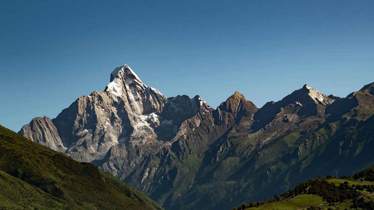 A stunning mountain range with snow-capped peaks under a clear blue sky, surrounded by lush green foothills — symbolizing the cooling impact of recent rain bringing relief from the heat across Pakistan.