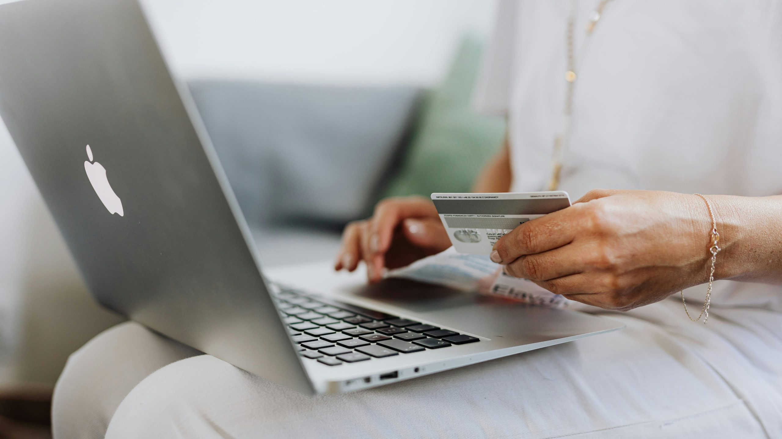 A person uses a credit card while shopping online on a MacBook, representing Pakistanis spending over Rs. 317 billion on online apps.