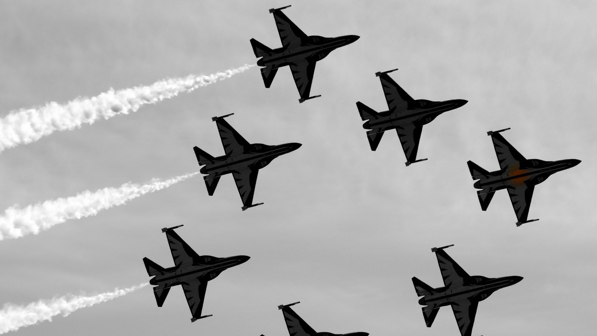 A group of fighter jets flies in close formation with white smoke trails against a grey sky, performing an aerial display ahead of RIAT.