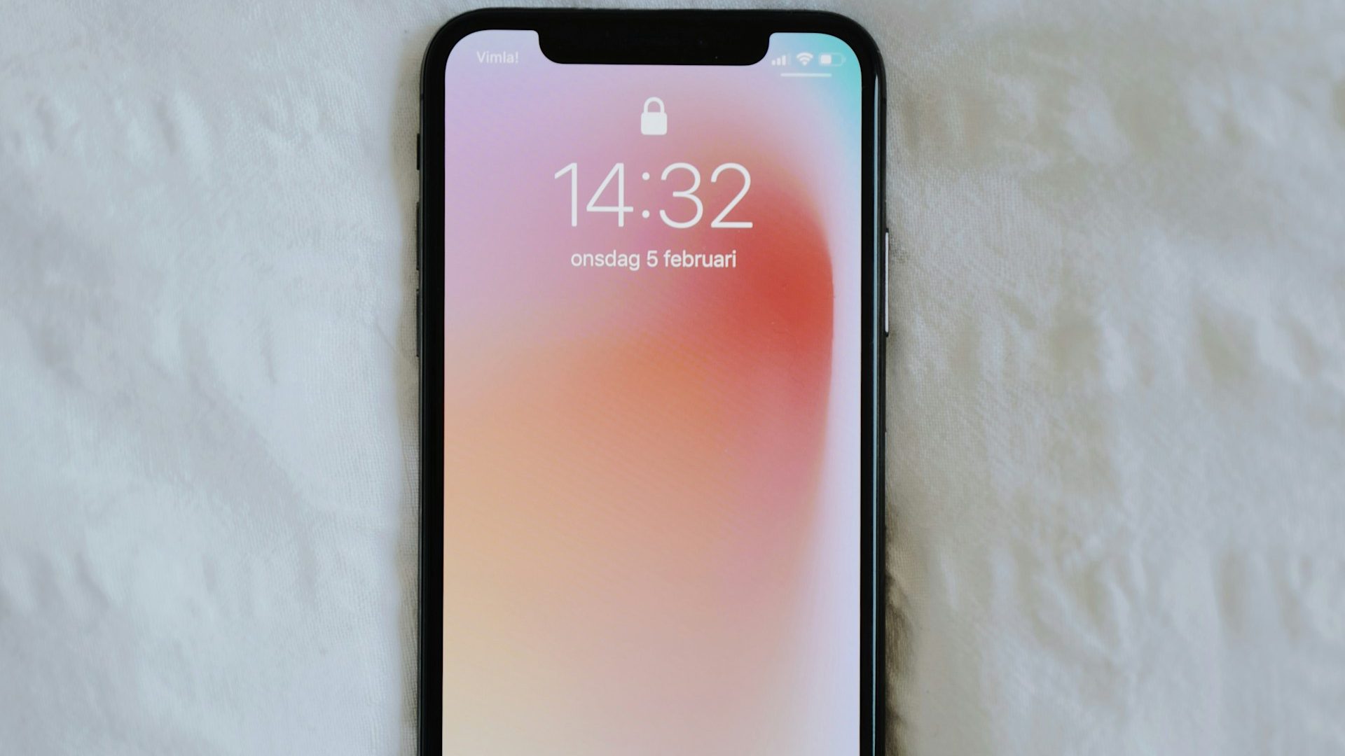 A smartphone displaying the lock screen placed on a white fabric surface, illustrating the importance of restarting your phone weekly for better performance.