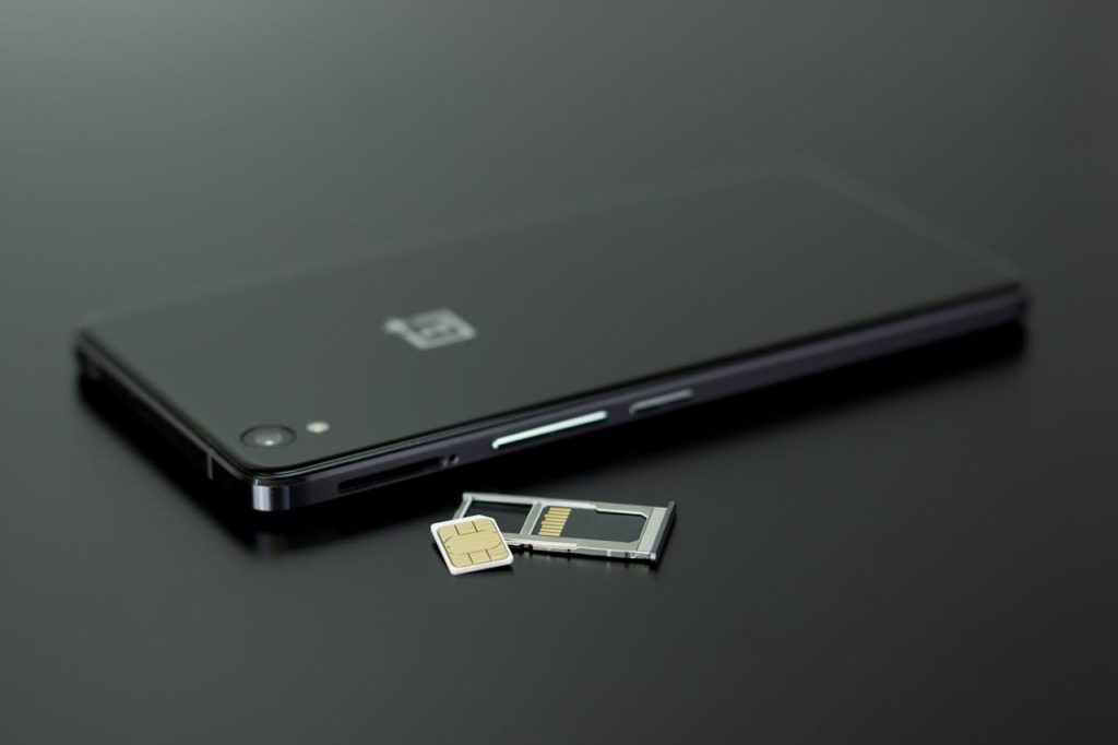 Tax-Free Mobile Registration for Overseas Pakistanis — A smartphone lies on a flat surface next to a SIM card tray and SIM card, symbolizing mobile phone use and registration processes for overseas Pakistanis.