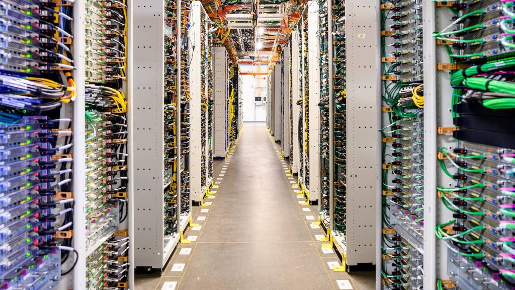 A high-tech aisle lined with dense server racks and vibrant network cables inside Meta’s AI data center, representing the world’s first gigawatt-scale AI supercluster built to power advanced superintelligence research and development.